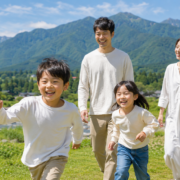 Family strolling along a riverside path with lush green mountains in Iiyama, Nagano