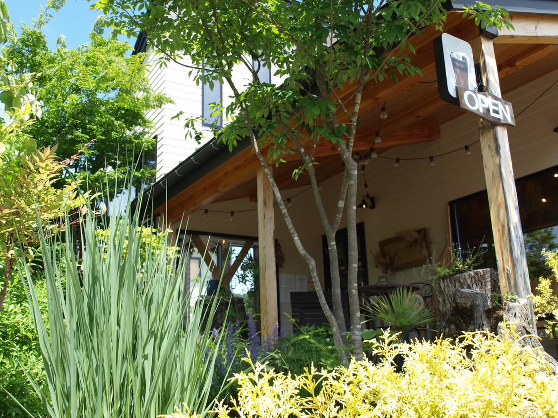 Green, plant-filled exterior of KOMOREBI nurseries with an OPEN sign