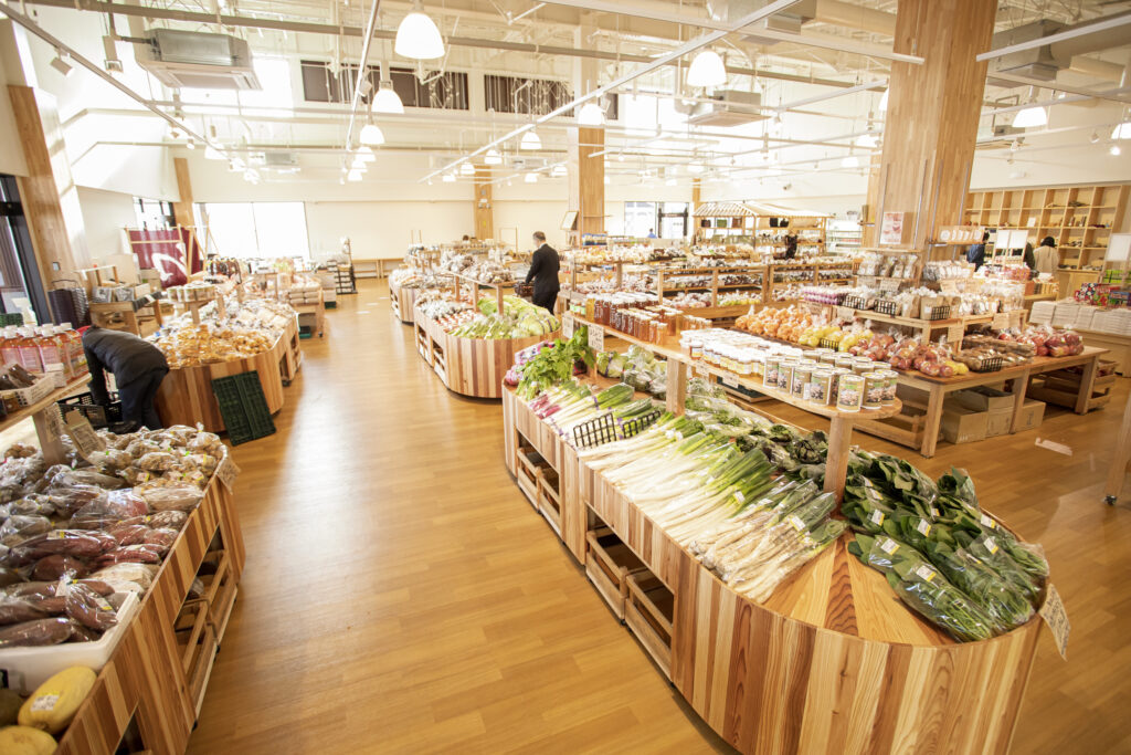 Local vegetables such as long green onions on wooden stands at the Hana no Eki Chikumagawa farmers market