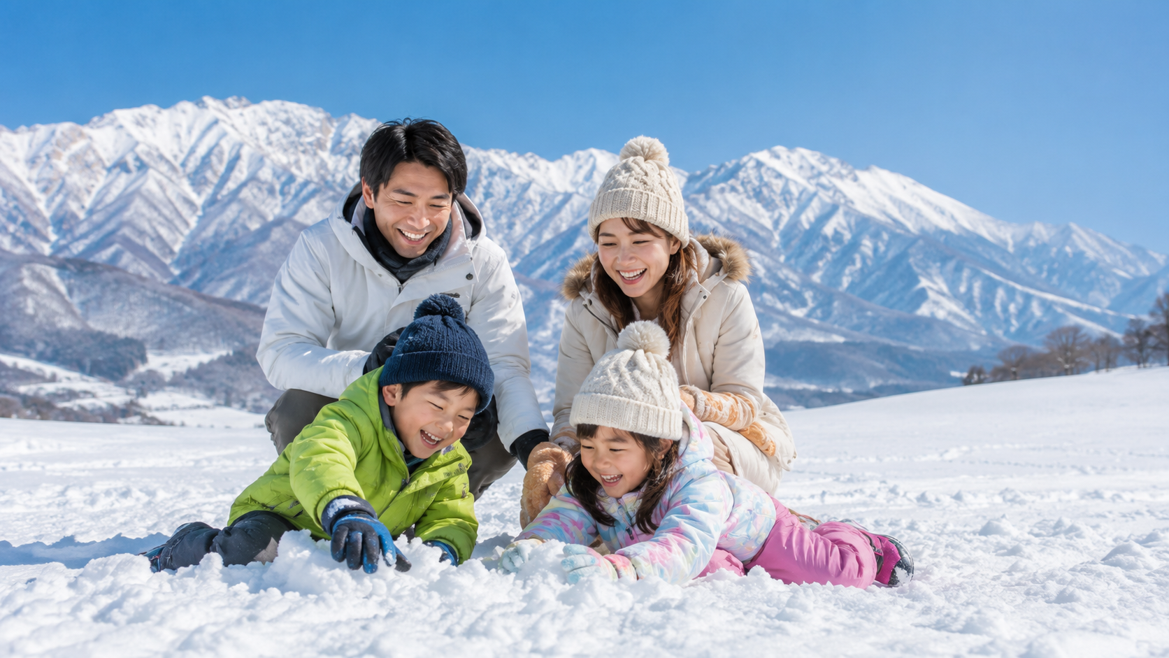 雪山を背景に親子4人が雪遊びを楽しむ冬の家族旅行風景